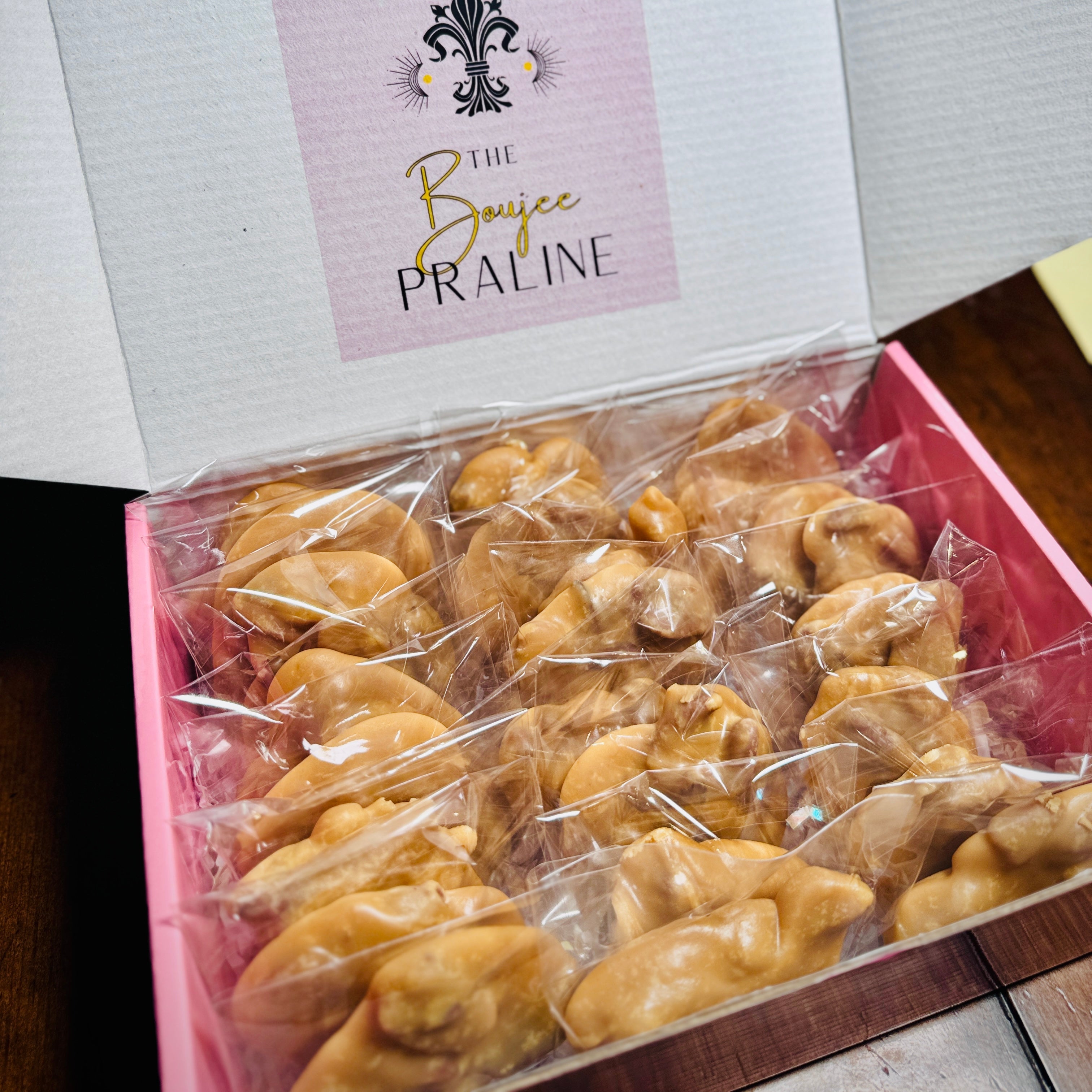 Box of pralines with 'The Boujee Praline' label on a wooden surface